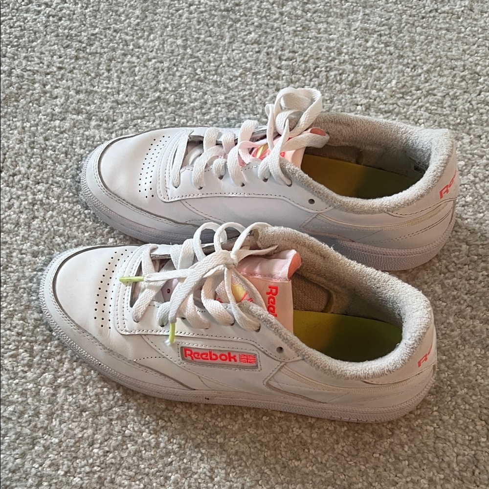 Reebok Woman white classic sneaker with neon orange detail.